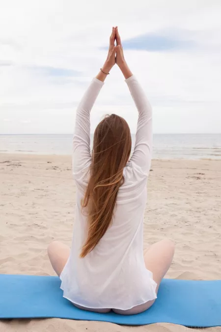 Матильда Сан на пляже в лотосовой позе